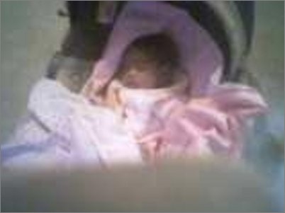 This baby was three weeks old and was resting comfortably in her car seat when the mother took a picture. After the picture was developed, she saw the gray image next to the baby that appeared to be another baby. The mother had lost her first baby due to a miscarriage and thinks that this was her lost baby coming to watch over her newborn sister. 