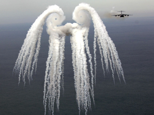 Smoke AngelThe cloud pictured above resulted from a series of flares released by an air force jet over the Atlantic Ocean in May. The jet that released the flares, a C-17 Globemaster III, is seen on the right. The flares release smoke and the resulting pattern is sometimes known as a smoke angel. The circular eyes of the above smoke angel are caused by air spiraling off the plane&rsquo;s wings and are known as wingtip vortices. (Source) 